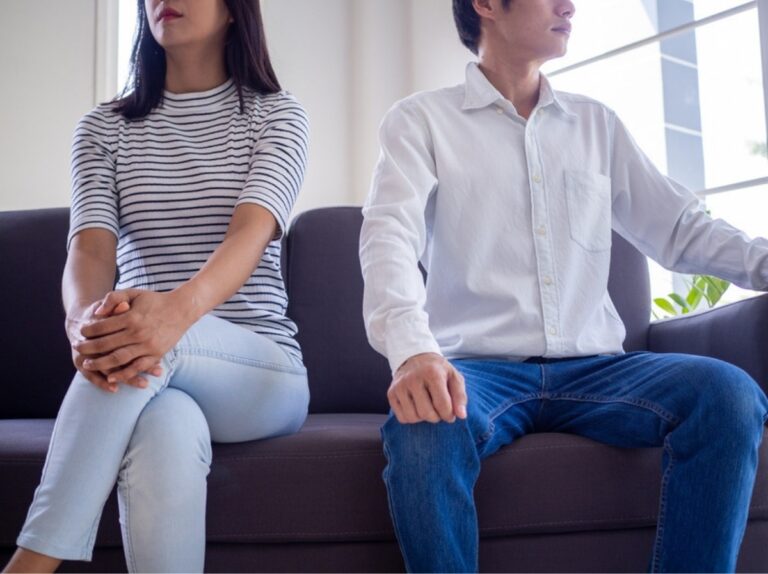 Anxious-avoidant relationship: a couple sits apart on a sofa, turned away from each other