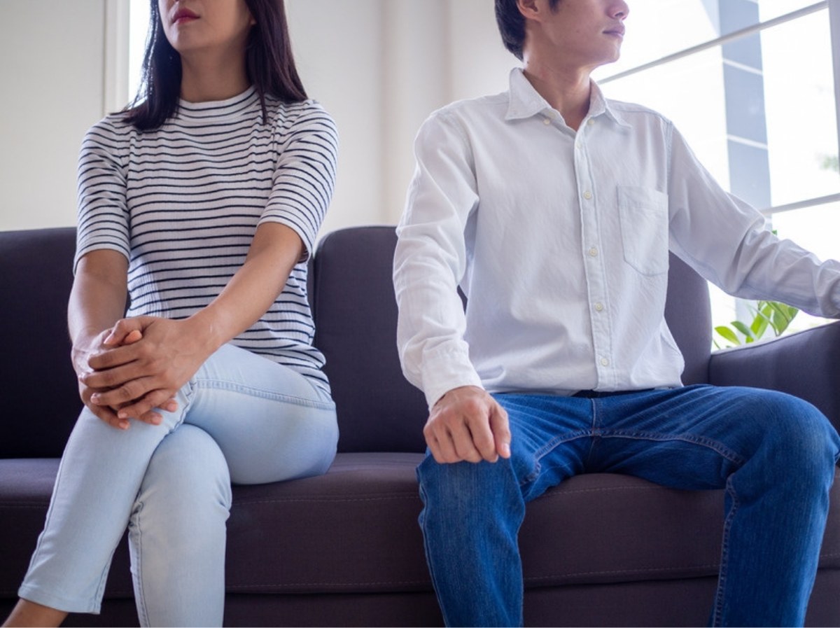Anxious-avoidant relationship: a couple sits apart on a sofa, turned away from each other