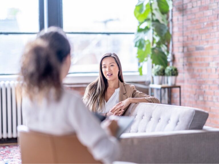 Brainspotting vs. EMDR: a client talks with her therapist in a bright, plant-filled office