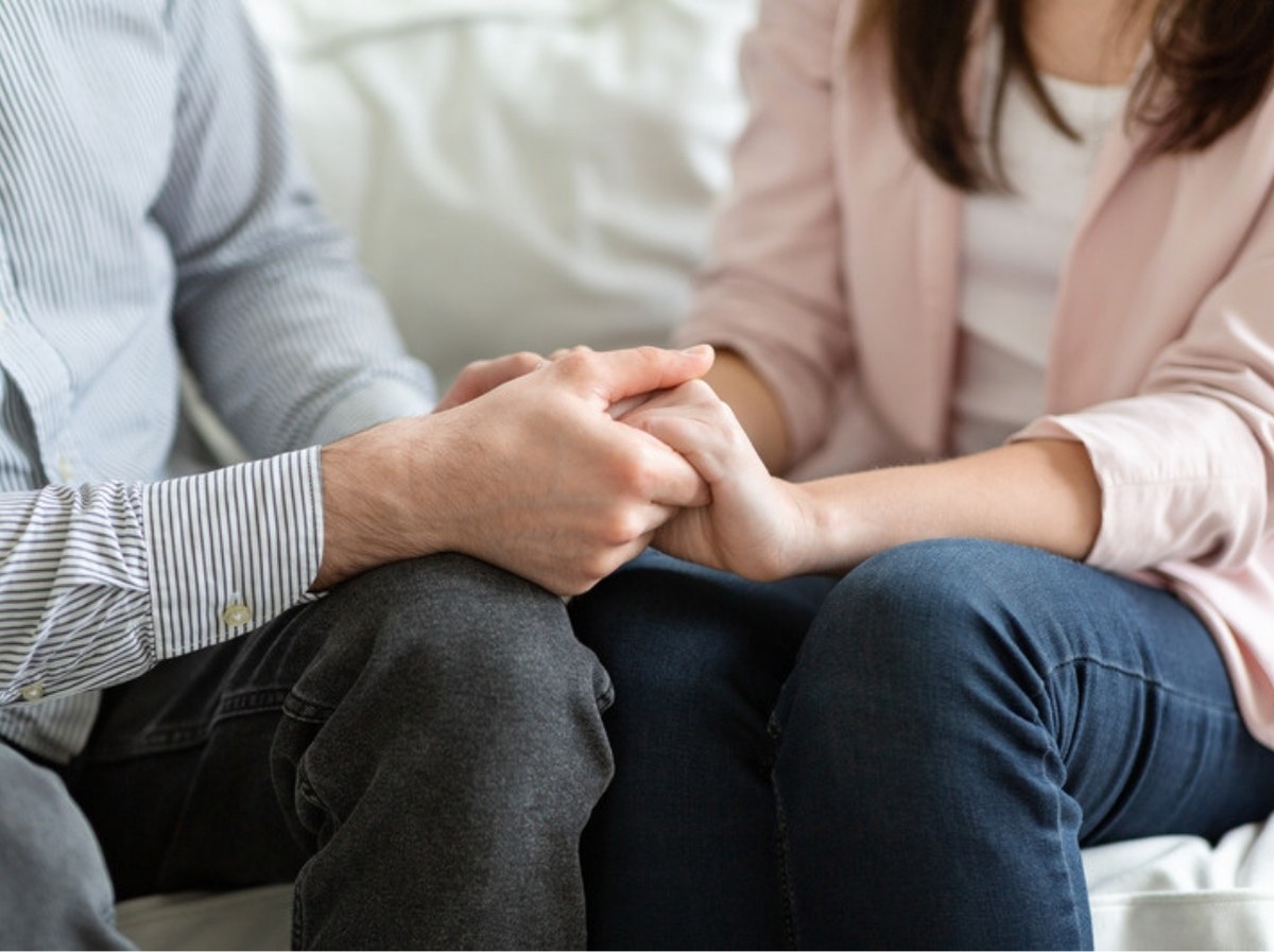 Can couples therapy save a marriage? A couple holds hands while sitting together on a sofa